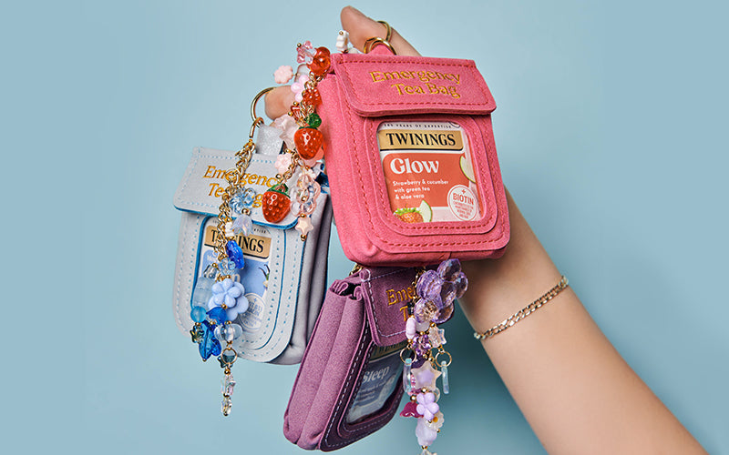 Pink tea bag-shaped pouch held by a hand against a light blue background