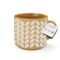 Mustard stoneware mug with repeating cream leaf pattern, glossy glaze and cylindrical shape.