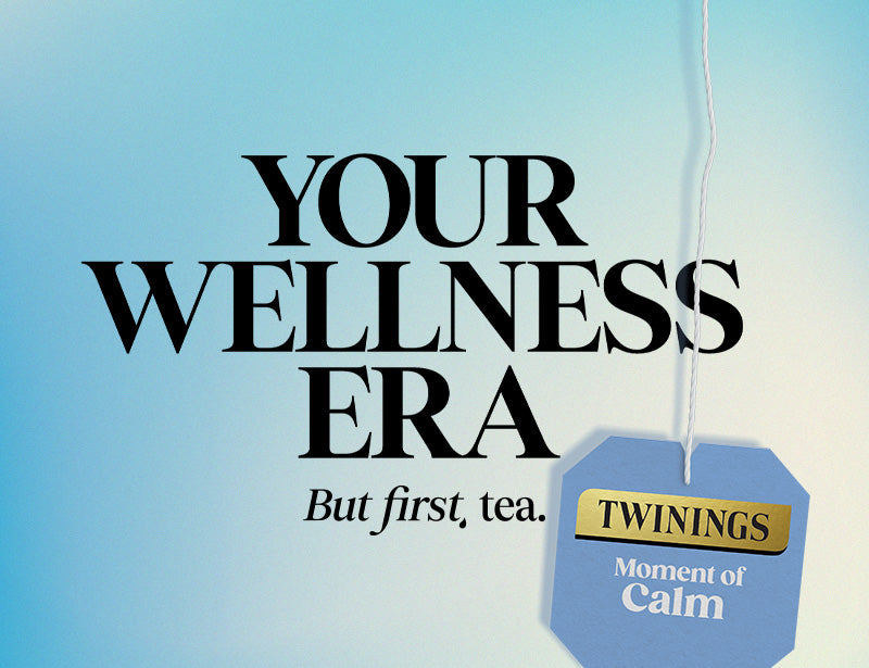 A light blue gradient background with large black text reading 'YOUR WELLNESS ERA' and smaller text 'But first, tea.' A hanging tea tag on the lower right reads 'TWININGS' and 'Moment of Calm.