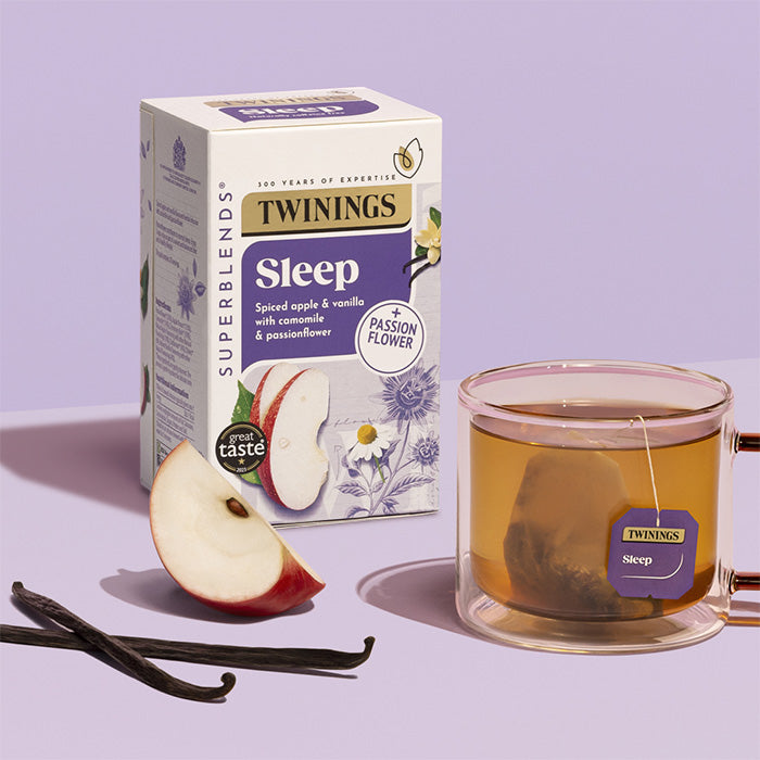 Twinings Sleep tea box with a glass of tea and ingredients on a purple background